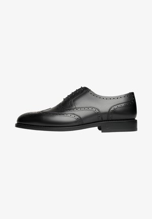 Zwarte leren dress shoe met een wingtip ontwerp, geperforeerde details en een ronde neus. Beschikt over een platte zool met subtiele stikselaccenten.