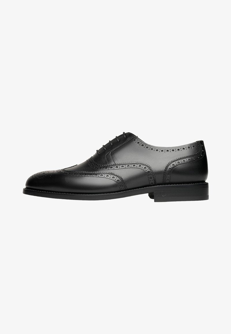 Scarpa da uomo in pelle nera con design wingtip, dettagli perforati e punta rotonda. Presenta una suola piatta con accenti di cucitura discreti.