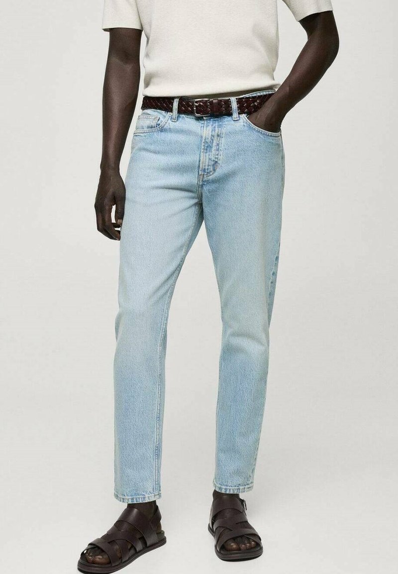 Jeans din denim de culoare albastru deschis, cu croi drept, asortați cu o curea din piele împletită de culoare maro și sandale de culoare maro închis, având o croială lejeră.