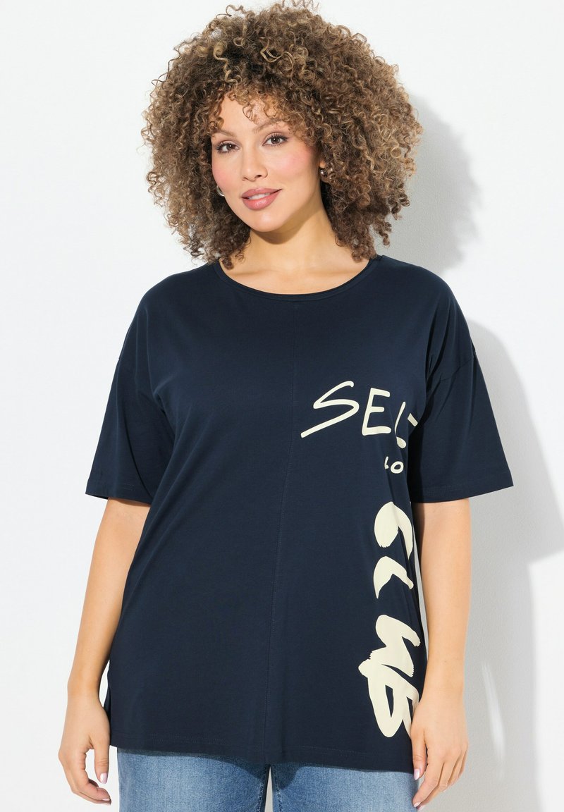 Camiseta de algodón azul marino con mangas cortas, con gran texto beige en el frente, ajuste relajado y cuello redondo.