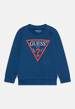 Felpa blu con maniche lunghe, polsini a costine e una grafica triangolare rossa. Presenta il testo "GUESS? U.S.A." in bianco e nero.