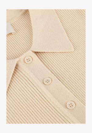 Close-up van beige ribgebreide stof met een kraag en drie bijpassende plastic knopen op een kledingstuk.