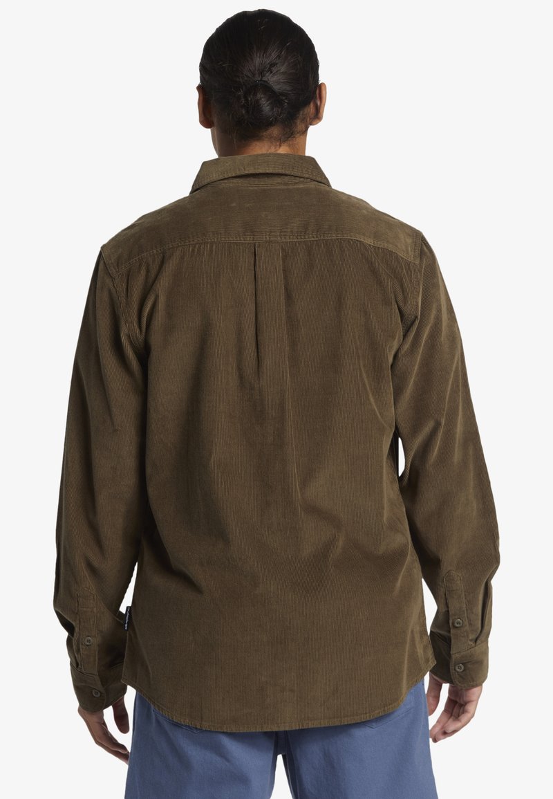 Camicia di velluto a coste marrone con colletto, polsini bottonati e una piega sul retro, dal fit rilassato e dalla texture a coste.