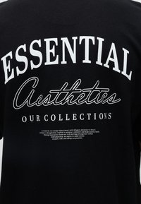 Μαύρο ύφασμα με λευκό κείμενο που λέει Essential Aesthetics Our Collections και μια μικρότερη παράγραφο για το σχεδιασμό και την τέχνη.