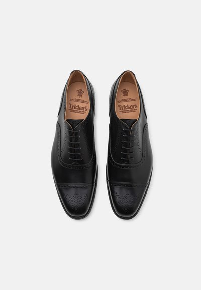 Scarpe da uomo in pelle nera con finitura liscia, caratterizzate da dettagli brogue sulla punta e da un design classico con lacci.