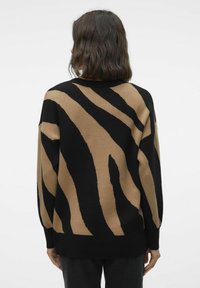 Pull rayé marron et noir avec une coupe ample, des manches longues et un col arrondi, présentant une texture tricotée douce et des épaules tombantes.