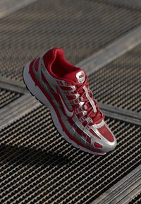 Rote und silberne Nike-Laufschuhe mit mesh-Obermaterial, geschwungener Silhouette und strukturiertem Außensohlensystem, ausgestattet mit weißem Logo und einem ausgeklügelten Schnürsystem.