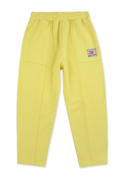 Pantalones de chándal amarillos hechos de una tela suave, con una cintura elástica, bolsillos laterales y un parche de logo colorido en el lado izquierdo.