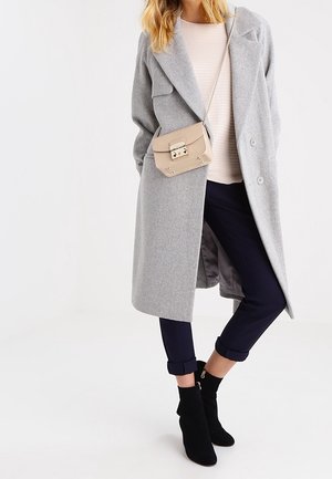 Lys grå uldfrakke, tætsiddende silhuet, store revers, parret med en beige crossover-taske, marineblå bukser og sorte tekstil ankelsko.