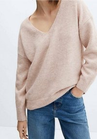 Lichtroze, loszittende trui met een diepe V-hals, geribde manchetten en zoom. Draag je met blauwe denim jeans, wat een casual stijl benadrukt.