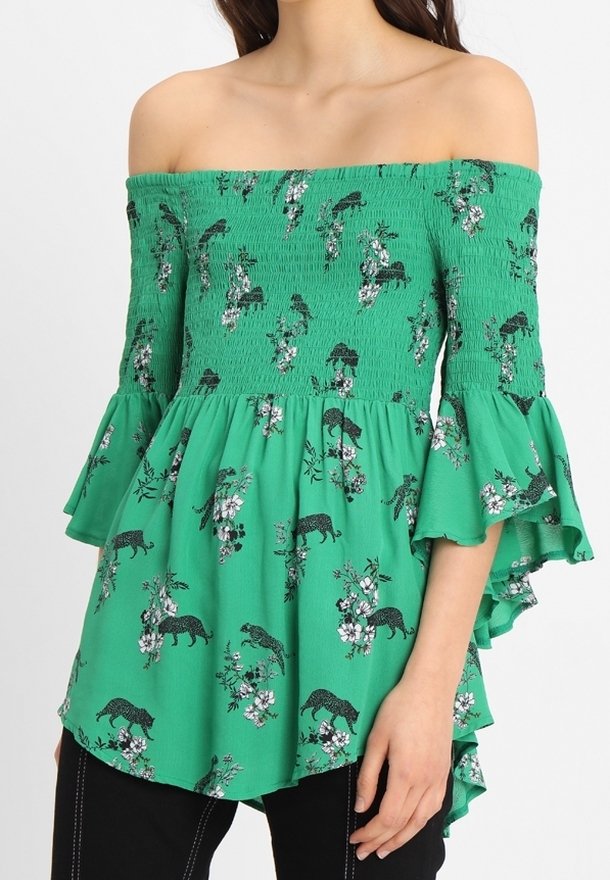 Blouse verte à épaules dénudées avec corsage plissé, manches évasées, et imprimés floraux et panthères. Tissu léger avec une silhouette fluide.