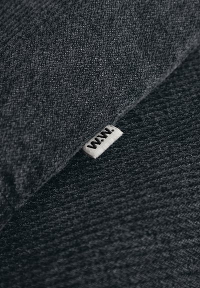 Teksturirani tamnosivi tkanina s tkanim uzorkom, s malom bijelom oznakom na kojoj je izvezeno "W.A.N.".