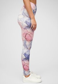 Leggings dalam pola cat air yang menampilkan nuansa merah muda, ungu, dan biru. Kain yang elastis dengan sabuk elastis, dipadukan dengan sepatu sneakers putih.