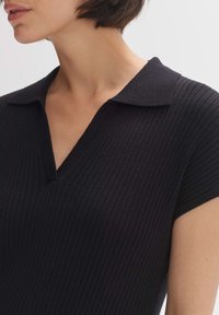 Top a coste nera con design a V colletto e maniche corte, che presenta un tessuto testurizzato e una vestibilità slim.