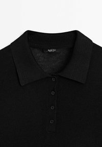 Mustapaita, jossa on neulottu pikee, ribbattu kaulus, viiden napin lista ja tekstuurivaihteluita. Etiketissä lukee "Massimo Dutti, valmistettu Kiinassa."