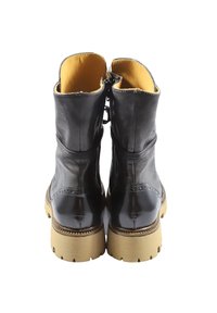 Stivaletti alla caviglia in pelle nera con finitura liscia, suola in gomma color cuoio, punta arrotondata e chiusura con zip posteriore. Interno foderato in tessuto giallo.