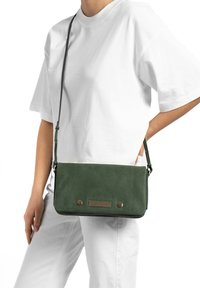 Groene leren schoudertas met een rechthoekige vorm, een textuurpaneel en bronzen hardware accenten. Inclusief verstelbare schouderband.