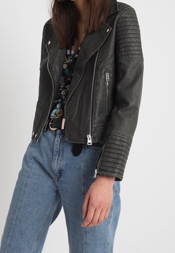 Czarna skórzana kurtka motocyklowa z żebrowanymi panelami na ramionach, zamkami błyskawicznymi i dopasowanym krojem, zestawiona z jasnoniebieskimi, wysokim stanem jeansami.