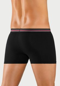 Black boxer briefs with a fitted design, featuring a contrasting striped waistband in red and white. Smooth texture, above-the-knee length.