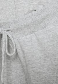 Grå joggebukser laget av myk, strukturert stoff, med elastisk midjebånd og snøring for justerbar passform.