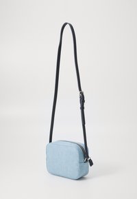 Bolso bandolera rectangular de color azul claro, con tejido texturizado, correa ajustable negra y cierre de cremallera plateado. Diseño simple y tamaño compacto.
