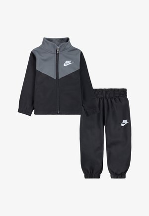 Trening Nike în două piese, cu jachetă cu fermoar și accente gri și pantaloni negri. Confecționat din material moale cu manșete și talie elastice.
