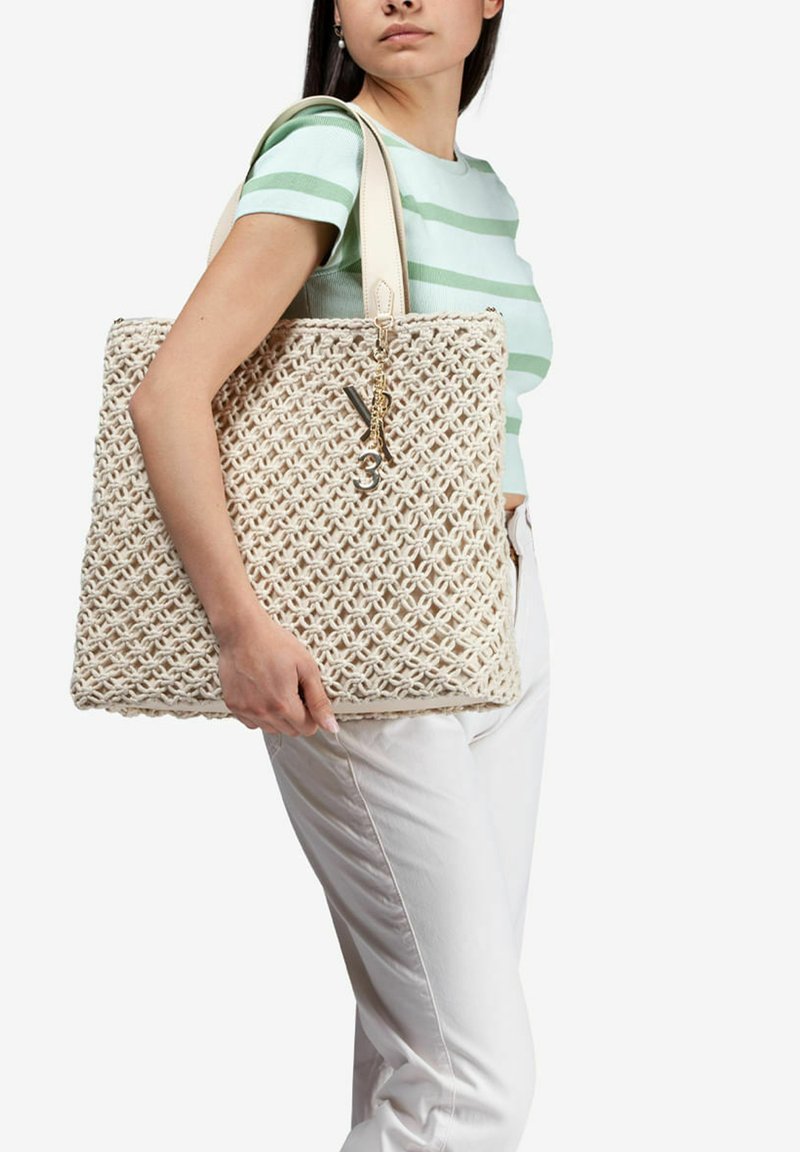 Borsa a spalla in paglia intrecciata di colore crema con un motivo geometrico, dotata di manici in pelle e un accento decorativo a forma di portachiavi.