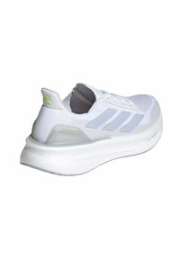 Scarpa da ginnastica bianca con accenti grigi, dotata di una tomaia in mesh traspirante, suola in schiuma spessa e supporto per il tallone trasparente etichettato "ULTRABOOST."