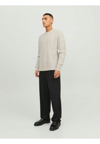 Light gray knitted sweater with textured cable patterns, rounded neckline, and long sleeves, paired with black wide-leg trousers and shoes.