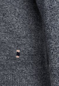 Dunkelgrauer Strickpullover mit texturiertem Muster. Enthält ein kleines Logoetikett in Rot, Weiß und Navy an der Seite. Weicher, dehnbarem Stoff.