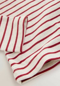 Cotton ribbed fabric featuring alternating red and cream stripes, with a folded edge showcasing the texture and color contrast.