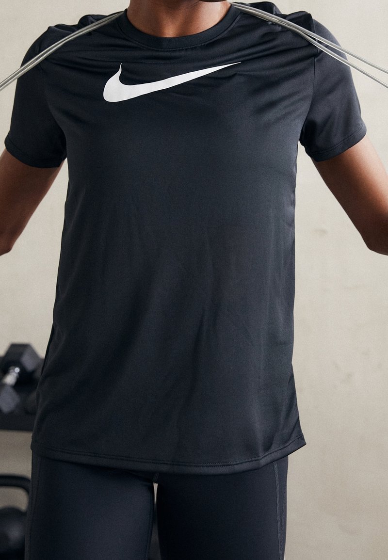 Camiseta deportiva negra de tejido suave con mangas cortas, que presenta un gran logo blanco de Nike en el pecho.