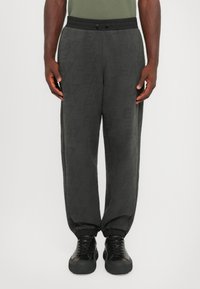 Gray sweatpants with a textured pattern, featuring an elastic waistband and cuffs, paired with black sneakers.