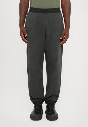 Grå joggebukser med et teksturert mønster, med elastisk midjebånd og mansjetter, kombinert med svarte joggesko.
