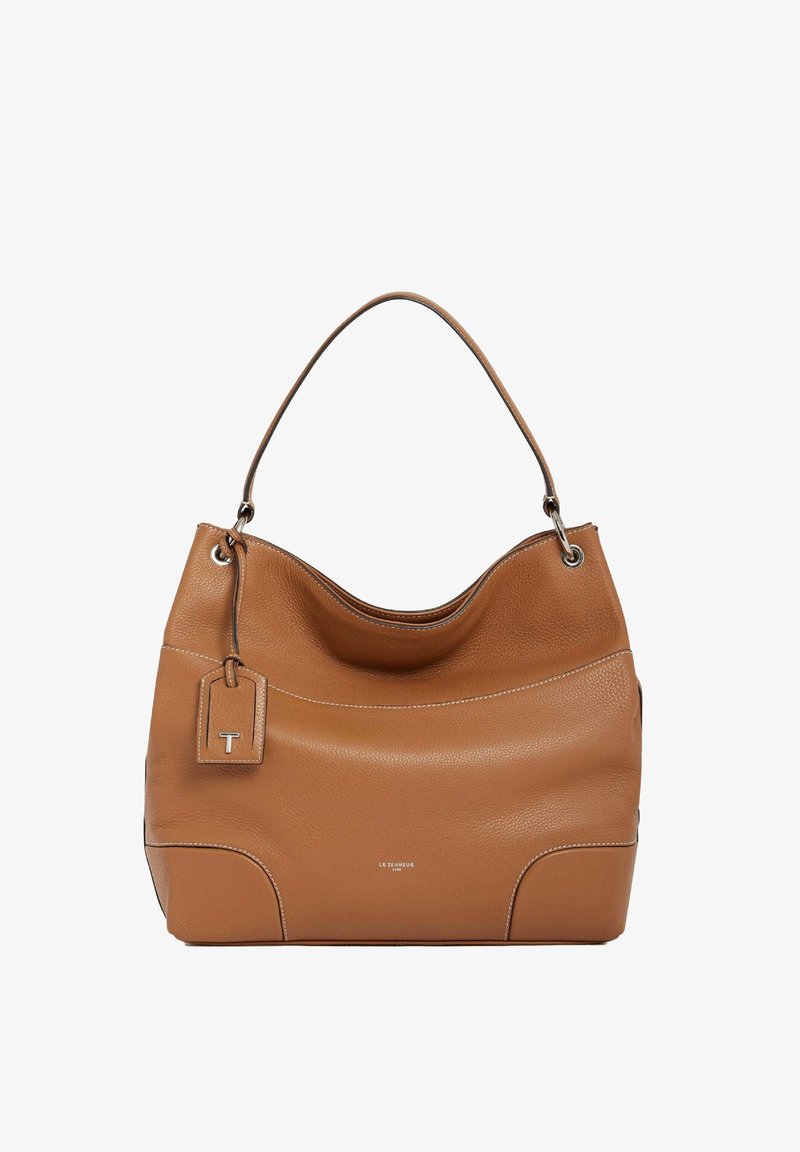 Sac à main en cuir tan avec une forme douce et arrondie. Il dispose d'une seule bandoulière, de coutures décoratives et d'une étiquette avec un logo.