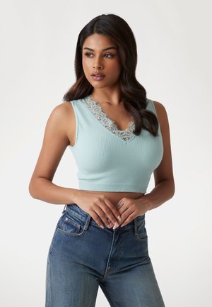 Crop top ribbed de culoare bleu deschis, cu decolteu în V și dantelă. Purtați-l cu blugi cu talie înaltă, punând în evidență țesătura netedă și designul ajustat.
