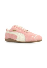 Sneakers Puma in morbido suede rosa chiaro con dettagli color crema. Presentano una suola testurizzata e un logo dorato a contrasto, progettati per comfort e stile.