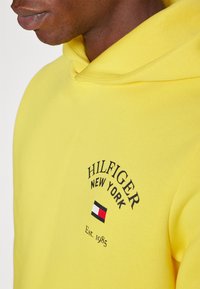 Tommy Hilfiger ARCHED VARSITY HOODY - Sportinis megztinis - eureka yellow