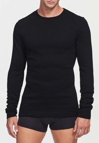 T-shirt nero a maniche lunghe realizzato in tessuto morbido, con collo rotondo e design aderente, texture liscia e senza motivi o componenti visibili.