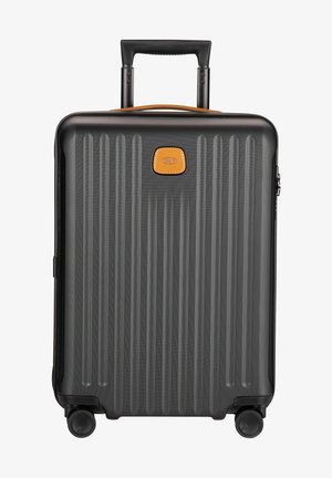 Valigia nera con texture rigata, manico retrattile, accento in pelle marrone e quattro ruote per la mobilità. Conforme alla Direttiva Europea sull'Accessibilità.