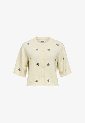 Cardigan crème à manches courtes boutonné avec des motifs de roses noires brodées uniformément espacés sur le devant et les manches.