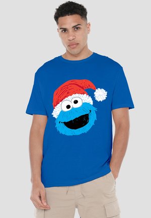 Kurzes, blaues T-Shirt mit einem großen, bunten Cookie Monster-Graphic, das einen roten Weihnachtsmannhut mit weißem Pompon trägt, aus Baumwollmaterial.