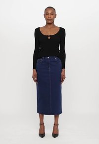 Bluză neagră cu mâneci lungi, având detaliu în formă de cheiță, asortată cu o fustă midi din denim de culoare albastră închisă. Material texturat cu cusături vizibile și buzunare frontale.