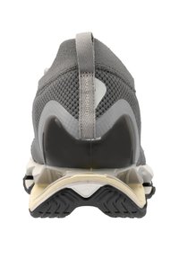 Scarpa sportiva grigia con tomaia in mesh testurizzato, design del tallone prominente e suola nera a contrasto. Presenta un'etichetta sul retro.