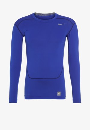 Camiseta de compresión Nike Pro Combat azul de manga larga con el logo Swoosh gris en el pecho y costuras cosidas que delinean el diseño.