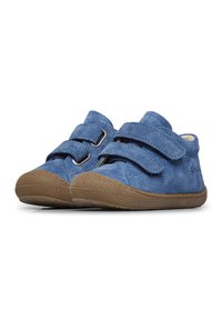 Des chaussures en daim bleu avec deux velcros, un bout arrondi et une semelle en caoutchouc marron texturée. Le design présente un style simple et fonctionnel.