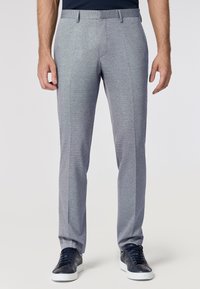 Pantaloni grigi su misura con una sottile trama testurizzata, a gamba dritta e con pieghe frontali, abbinati a sneaker scure.