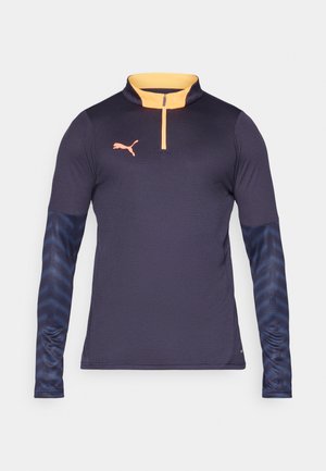 Tumes sleeve'iga sportlik jakk tumesinises, millel on oranž pooltõmbluku kaelus, tekstureeritud siniste varrukatega, millel on õrn muster ja logo rinnal.