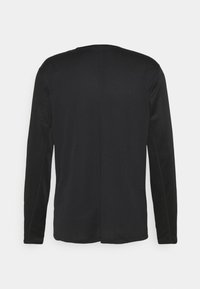 Mustat pitkähihaiset crew neck -paidat näkyvät takaa, ja keskellä on näkyvä pystysauma.