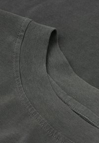 Czarna, ciemnoszara koszulka bawełniana z okrągłym dekoltem i gładką fakturą, z kontrastowymi przeszyciami wzdłuż krawędzi.